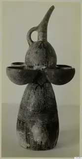 Pottery vessel with a tall curved spout, loop handle and two side cups, decorated with incised patterns