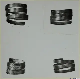 Four spiral metal rings from the Vrysi tou Barba tombs at Lapithos, shown on a photo mount