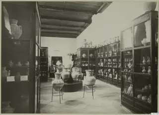 Interior of the Cyprus Museum with glass cabinets of pottery and large decorated jars on metal stands