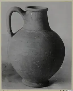 Plain pottery jug with a single loop handle and wide mouth, photographed against a plain grey backdrop