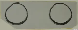 Two gold earrings, probably from Tomb 417 at Lapithos, shown side by side on a grey card.