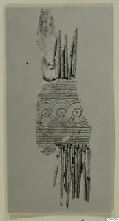 Carved bone fragment, possibly part of a comb, with incised bands and a scroll pattern