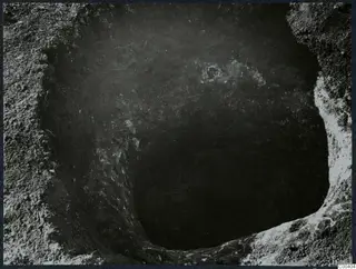 Tomb at Milia: looking down into a tomb chamber during excavation, with pale stones visible near the top
