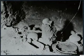 Tomb 11 at Milia: tomb chamber during excavation, with pottery vessels and bones lying on the floor.