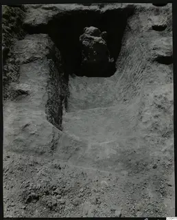Dromos of Tomb 317 at Lapithos, a sloping cut passage with a large stone blocking the dark opening at its far end