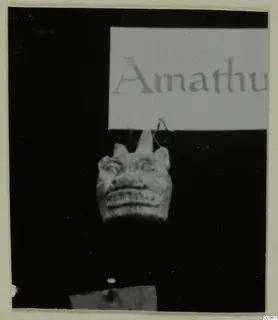 Small carved stone head with a card label above it, from Tomb 317 at Lapithos