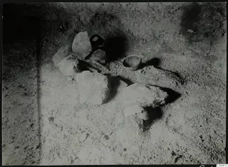 Tomb 317 at Lapithos, interior: a handled vessel, a small bowl and pale lumps on a sandy tomb floor