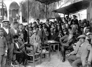 Crowd of men and a seated woman at a kafeneion café terrace in Kalavasos