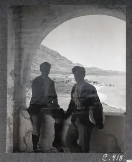 Two men at an arched vault, with the sea and mountains in the background