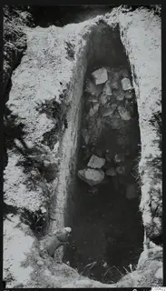 Excavation of Tomb 428 at Lapithos, showing a narrow cut in the earth filled with stones.