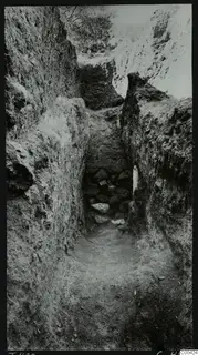 Dromos of Tomb 420 at Lapithos Kastros, a narrow cut passage with stones at its far end
