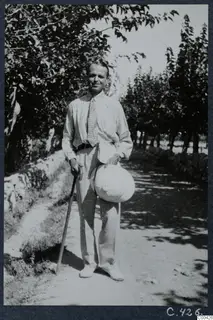 Erik Sjöqvist standing on a shady track at Lapithos, holding a walking stick and a pale hat.