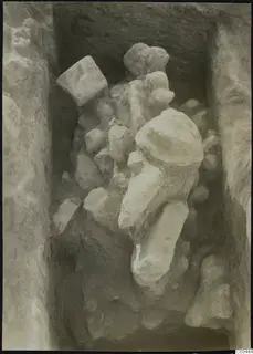 Excavation trench at Plakes, Lapithos, with stones and a large pale stone object lying among them