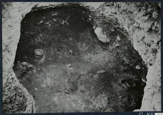 Tomb 66 at Marion during excavation, with small vessels and stones lying on the chamber floor