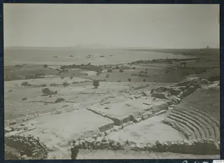 The theatre at Soli, with curved stone seating above a bay where several small boats float