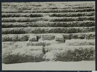 Stepped horizontal tiers of excavated earth at the theatre at Soli, with two stone blocks set into one step.