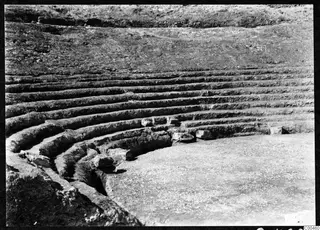 Curved tiers of stone steps at the theatre at Soli, with a flat paved area in the foreground
