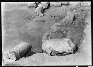 Excavation at Soli with large fallen stone blocks and a column drum lying beside an open trench.