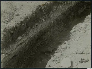 Excavation trench at Soli showing layered dark soil and stones in its sides