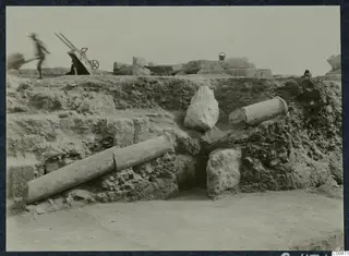 Two column drums and a carved fragment lying in an excavated trench at the theatre at Soli