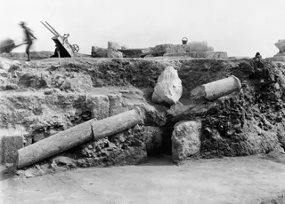 Column drums and a carved stone fragment lying in excavated ground at the theatre at Soli