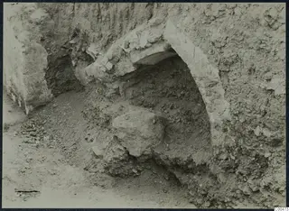 Excavation at Soli showing a curved stone construction set into a cut face of soil