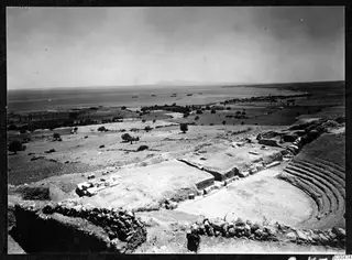 Excavated theatre at Soli seen from above, with curved stone seating rows and the sea beyond