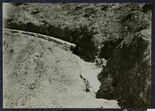 Excavation at Soli theatre showing a curved line of stones and a wall edge along a cut trench