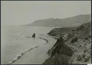 Coastline below the Kyrenia Mountains, with a sandy bay, a offshore rock stack and scrub-covered slopes.