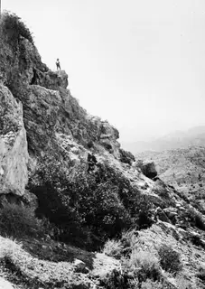 Steep rocky south-west slope at Vouni, with one man standing on a rock ledge near the top.