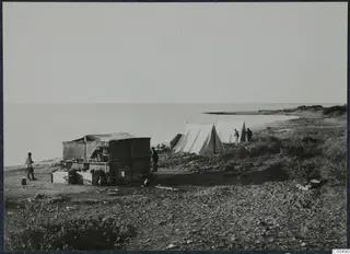Tents, people and pottery vessels on the shore at Oura