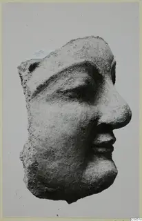 Head fragment of a small statuette in profile facing right, with a broken top and back.