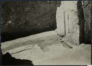 Excavated flagstones and a pale plastered wall in a trench at Vouni palace
