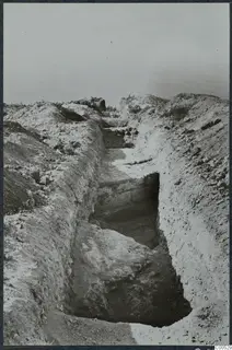 Excavation trench with loose stones along its banks at Vouni, with the sea visible in the background.