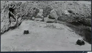 Finds in situ in an excavated trench at Vouni Palace, with stone pieces lying on a cleared floor against an earth face.