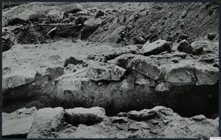 Excavation at the Temple of Athena, Vouni, with large stone blocks in a trench and a spade at the upper left