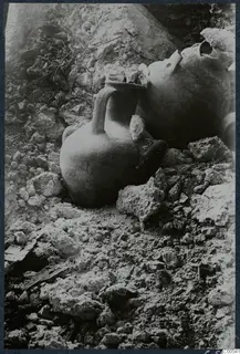 Two vessels lying among stones and rubble at Vouni, one a small jug with a strap handle.