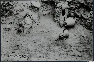 Pottery vessels and stones lying in excavated soil at Vouni