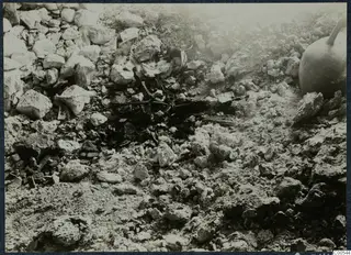 Loose stones and fragments on excavated ground at Vouni Palace, with a large vessel at the right edge