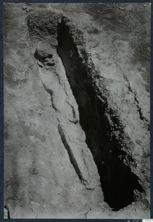Narrow excavation trench at Vouni with a rounded stone and a line of stones along its edge