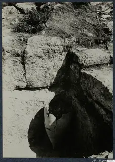 Large broken pottery vessel lying in situ in an excavated pit beside cut stone blocks at Vouni Palace