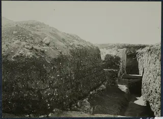 Excavation trench at Vouni with stone walls and a large earth bank on the left.