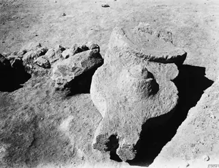 Large weathered stone object and rubble lying in excavated ground at Vouni Palace