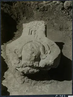 Carved stone block with a relief head-like form, lying in an excavated trench at Vouni Palace