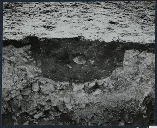 Close view of an excavated section at Vouni, showing stones and a dark soil fill between layers of rubble