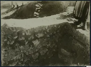 Excavation at Vouni palace: a person stands at the edge of a trench beside a cut face of stones and soil.