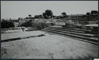 Broad stone steps and low ruined walls at Vouni Palace, with people and trees in the background.