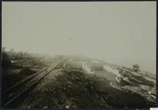 Excavation at the palace at Vouni with stone walls, a rail track and a tipping wagon, partly hidden in mist