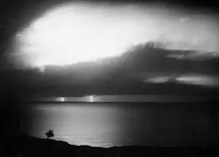 Night thunderstorm over the sea at Vouni, with lightning strikes on the horizon and a lone tree on the hillside edge