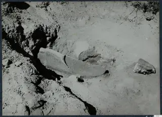 Excavation at Vouni with a long worked stone object lying in situ in the soil, Room 122
